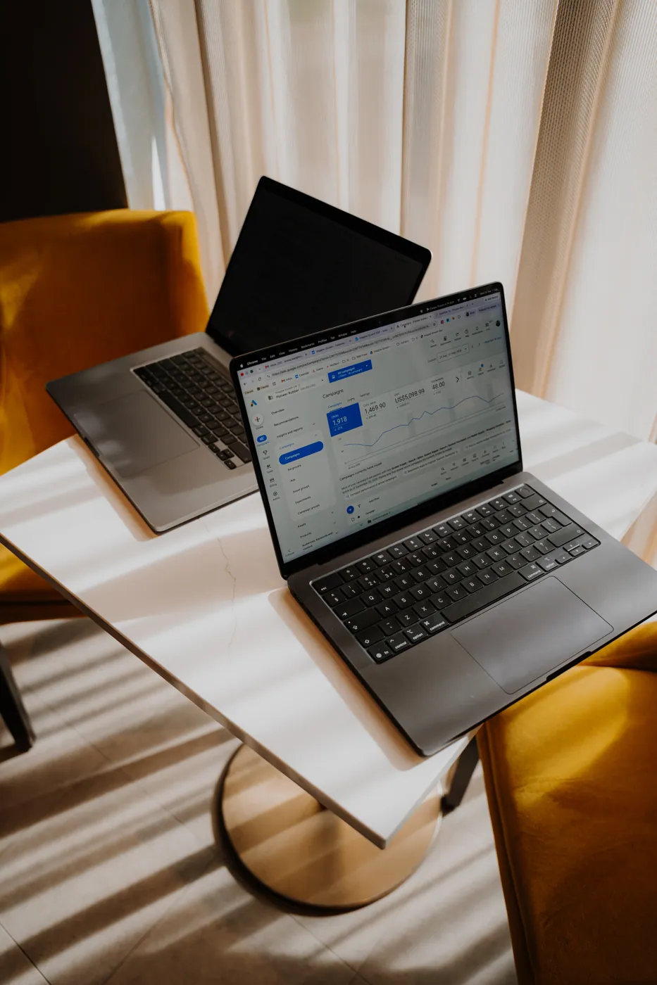Two laptops on a table in the window light
