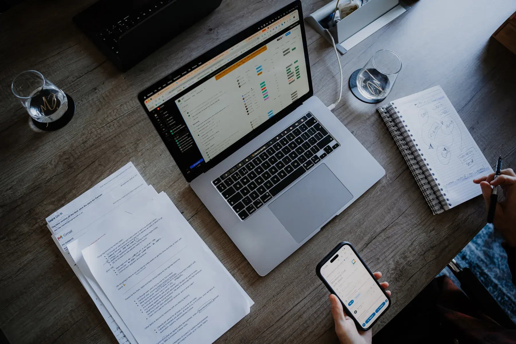 A laptop, papers and a phone on the table, from above